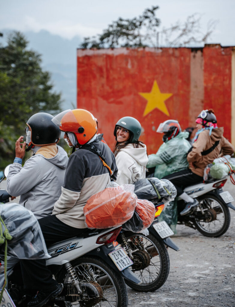 Ha Giang Safari group motorcycle tour riding the Ha Giang Loop with Vietnam star in the background