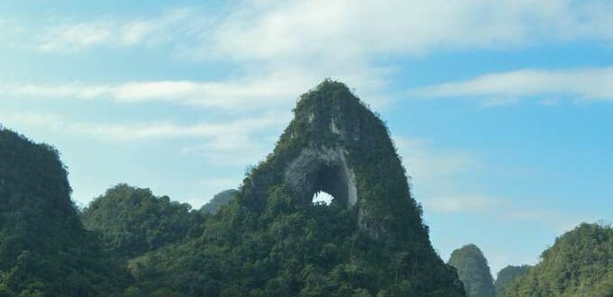 Girl in front of mountain with natural hole in it