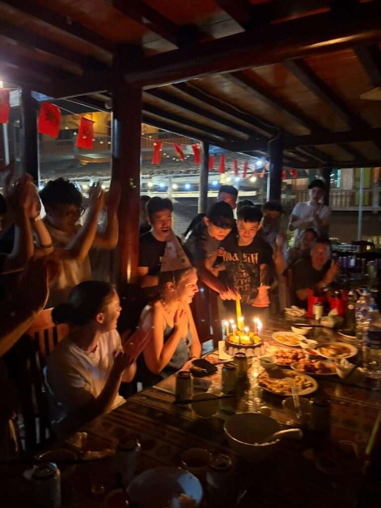 Group celebrating a birthday dinner during a Ha Giang Safari homestay night