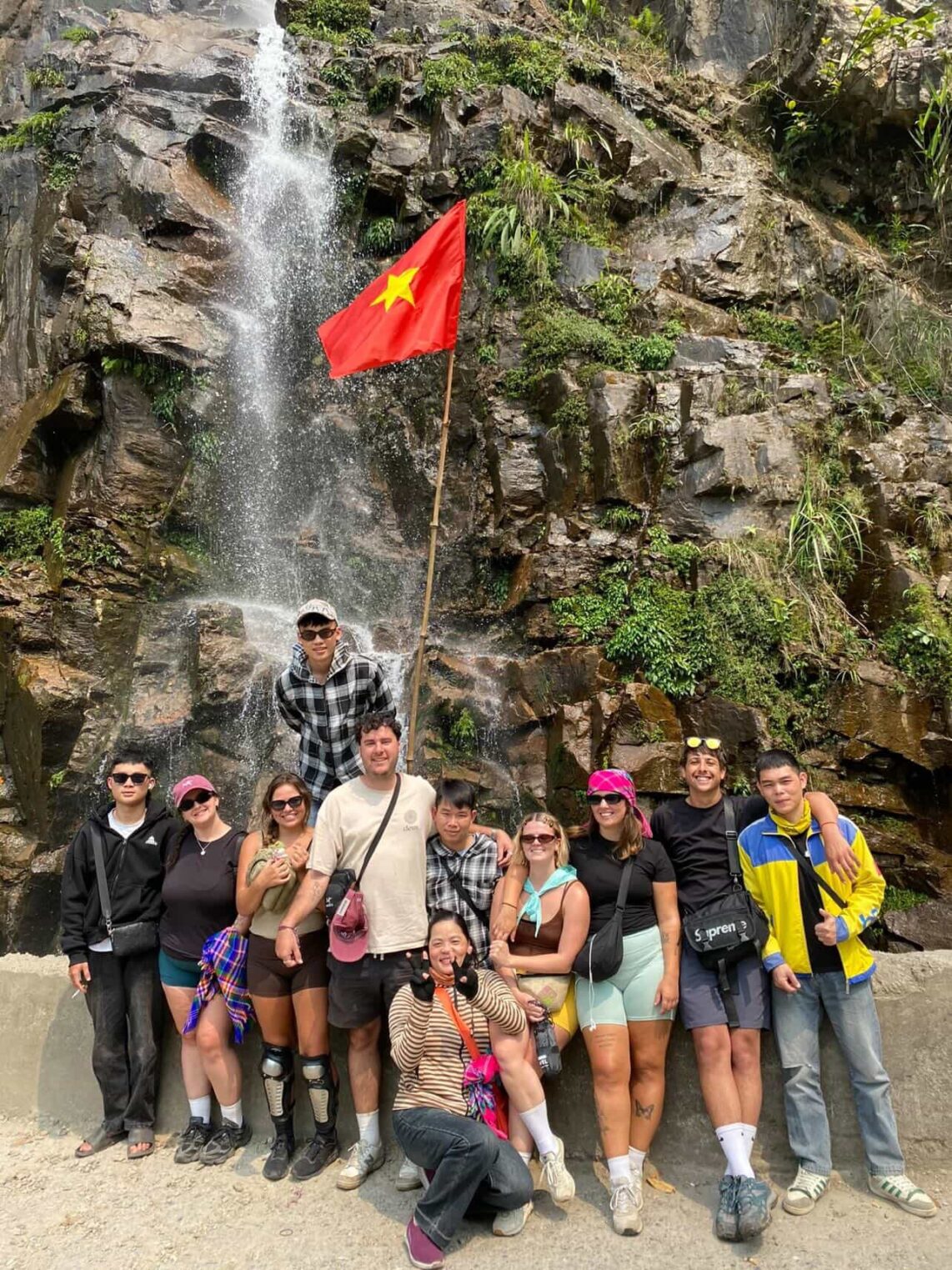Small group photo of guests with easy riders at waterfall on the Ha Giang Loop
