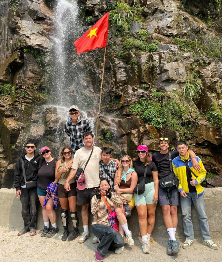 Small group photo of guests with easy riders at waterfall on the Ha Giang Loop